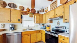 Una cocina con armarios de madera, lavavajillas de acero inoxidable, estufa y refrigerador.