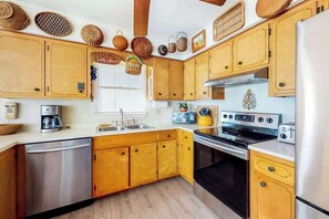 A kitchen with wooden cabinets, a stainless steel dishwasher, a stove, and a refrigerator. - Canal-front home with boat dock, large deck, AC, washer/dryer & WiFi (Ocean City)