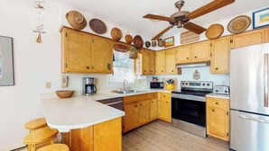 Una cocina con armarios de madera, una isla central, una estufa, un microondas y un refrigerador.