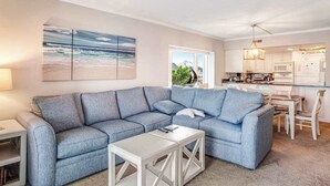 Ein Wohnzimmer mit Ecksofa, Couchtisch und Blick auf die Küche und den Essbereich.