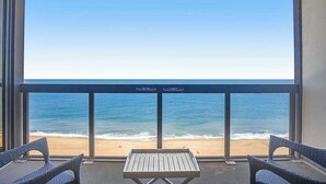 Un balcon donnant sur la plage, deux fauteuils en osier et une petite table.