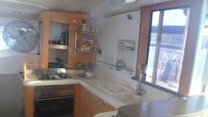 Une cuisine de taille réduite, équipée d’une cuisinière, d’un four, d’un évier et de meubles de rangement en bois.