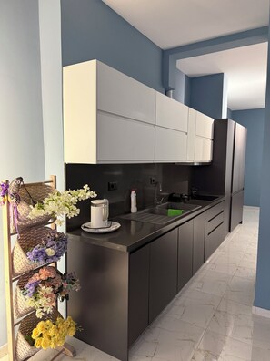 A modern kitchen with dark cabinets, a black countertop, and a built-in sink. - RIO Apartments Saranda 1 (Sarandë)