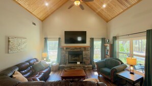 A living room with a fireplace, leather sofa, and a television.