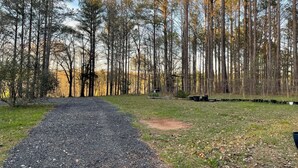 A gravel path leading through a forested area with tall trees and a clear sky.