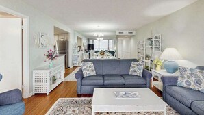 Ein modernes Wohnzimmer mit einem grauen Sofa, einem weißen Couchtisch und einem gemusterten Teppich.