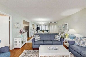 Ein modernes Wohnzimmer mit einem grauen Sofa, einem weißen Couchtisch und einem gemusterten Teppich.