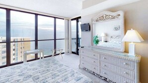 Una camera da letto con un'ampia finestra, un letto, una cassettiera e una TV.