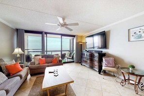 Ein Wohnzimmer mit Sofa, Couchtisch, Fernseher und Balkonblick.