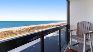A balcony with a view of the beach, a chair, and a sign warning against railing use. - Waterfront condo with balcony, AC, tennis, pools & gym (Ocean City)