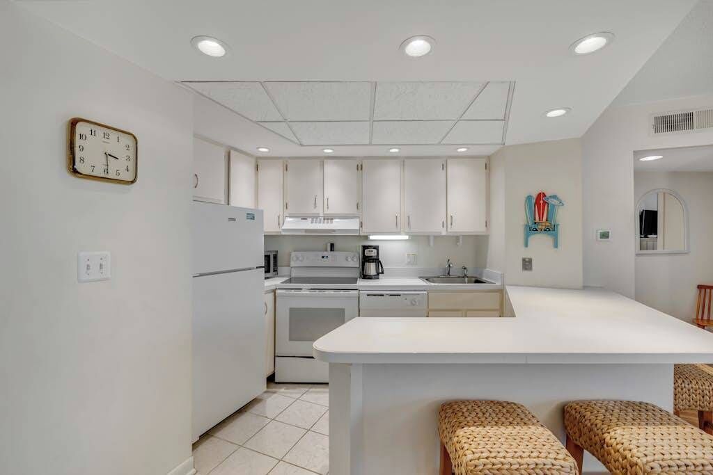 Una cocina moderna con armarios blancos, una isla central y un reloj en la pared.