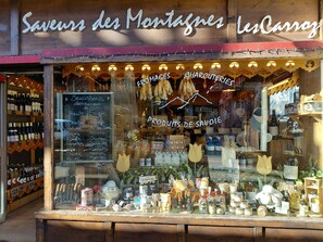 A storefront with a wooden sign, a chalkboard menu, and various products displayed in the window. - Comfortable studio in resort center (Arâches-la-Frasse)
