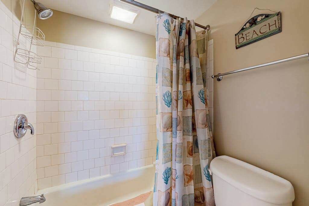 A bathroom with a shower, a toilet, and a towel rack.