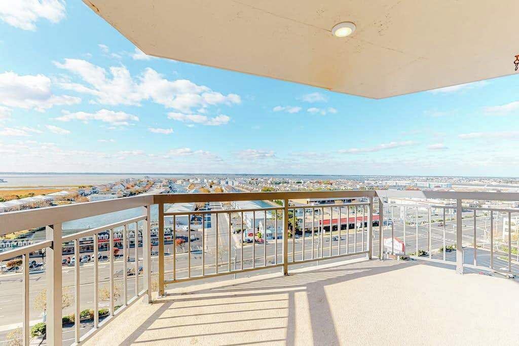 Ein Balkon mit Blick auf einen Parkplatz und entfernte Gebäude.