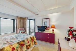 Ein Hotelzimmer mit Bett, Fernseher, Kommode, Lampe und Meerblick.