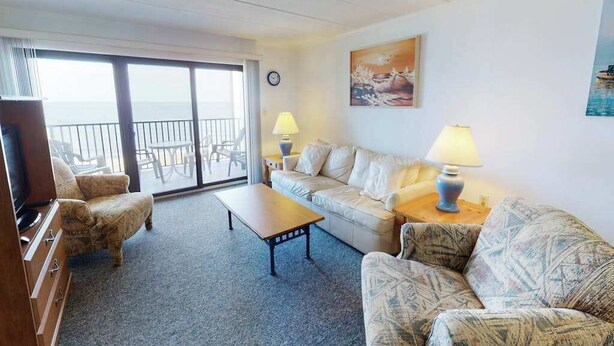 A hotel room with a sofa, armchair, and a TV. There is a balcony with a view of the sea. - Beachfront Suite w/Ocean Views From Balcony, Free WiFi, Central AC, Private W/D (Ocean City)