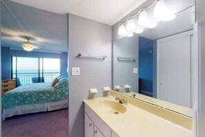 A bedroom with a bed, a bathroom with a sink and mirror, and a balcony with a view. - Fountainhead Towers 906 (Ocean City)