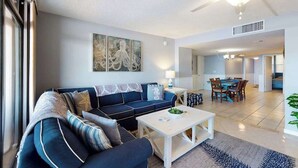 A living room with a sofa, coffee table, and artwork on the wall. - Fountainhead Towers 906 (Ocean City)