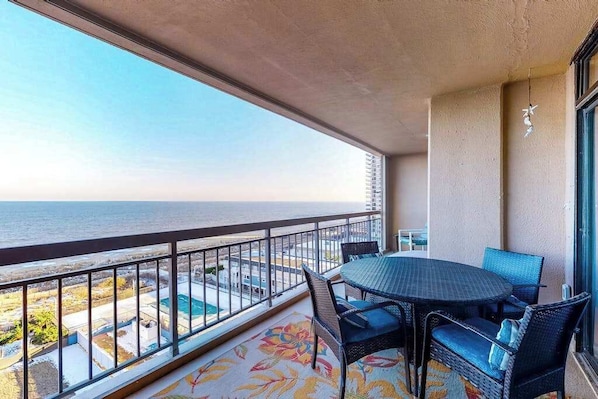 A balcony with a view of the ocean, a round table, and wicker chairs. - Fountainhead Towers 906 (Ocean City)