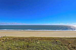 A beach with a clear sky, sandy shore, and grassy dunes. - Sunny Beachfront Condo w/Private Balcony, Washer/Dryer, A/C, Free WiFi, Views (Ocean City)