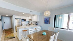 Een moderne keuken met witte kasten, een houten eettafel en een groot raam.
