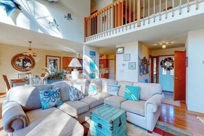 A spacious living area with a high ceiling, a staircase, and a dining area. - Dove Lane 8 (Ocean Pines)