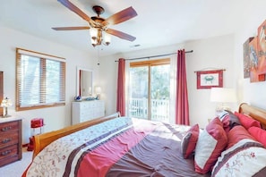A bedroom with a bed, a ceiling fan, a dresser, a window with blinds, a door, and a balcony with a view. - Dove Lane 8 (Ocean Pines)