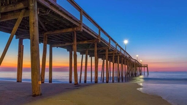 A wooden pier extending into calm waters at sunset. - Endless Summer (Ocean City)