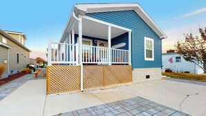 A single-story house with a covered porch, a wooden fence, and a flag. - Endless Summer (Ocean City)