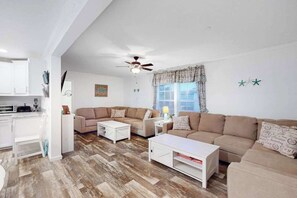 Ein modernes Wohnzimmer mit einer Couch, einem Couchtisch und einem Deckenventilator.