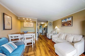 A living room with a sofa, chairs, a dining table, and artwork on the walls. - Amazing Suite in Oceanside Building w/Shared Pool, Private Washer/Dryer, WiFi (Ocean City)