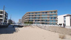 Un hotel de varios pisos con un diseño moderno, situado cerca de una playa de arena.