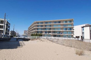 A multi-story hotel with a modern design, located near a sandy beach. - Amazing Suite in Oceanside Building w/Shared Pool, Private Washer/Dryer, WiFi (Ocean City)