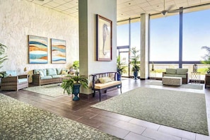 A spacious lobby with a high ceiling, large windows, and a variety of seating arrangements including sofas and chairs. - Lovely Condo in Beachfront Building w/Shared Pool, Free WiFi, Central AC (Ocean City)