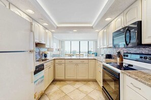 A modern kitchen with white cabinetry, a large island, a built-in oven, and a microwave. - Lovely Condo in Beachfront Building w/Shared Pool, Free WiFi, Central AC (Ocean City)