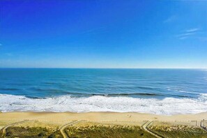 A beach with a clear sky, waves, and a sandy shore. - Waterfront condo with balcony, views, pools, gym, & sauna (Ocean City)