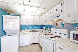 A kitchen with white appliances, blue walls, and a tiled floor. - Bright Condo w/Private Balcony, Beach Views, Shared Pools, Gym, A/C, Free WiFi (Ocean City)