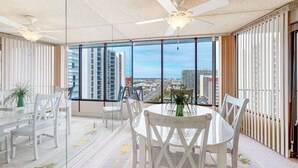 Una habitación amplia con un gran ventanal, un ventilador de techo y una mesa redonda con sillas.