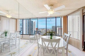 A spacious room with a large window, a ceiling fan, and a round table with chairs. - Bright Condo w/Private Balcony, Beach Views, Shared Pools, Gym, A/C, Free WiFi (Ocean City)