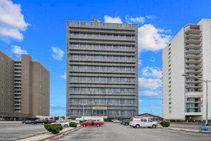 A multi-story hotel with a modern design, featuring a central entrance and a parking lot in front. - Wonderful Suite in Beachfront Complex w/Shared Pool, Free WiFi, Private W/D (Ocean City)