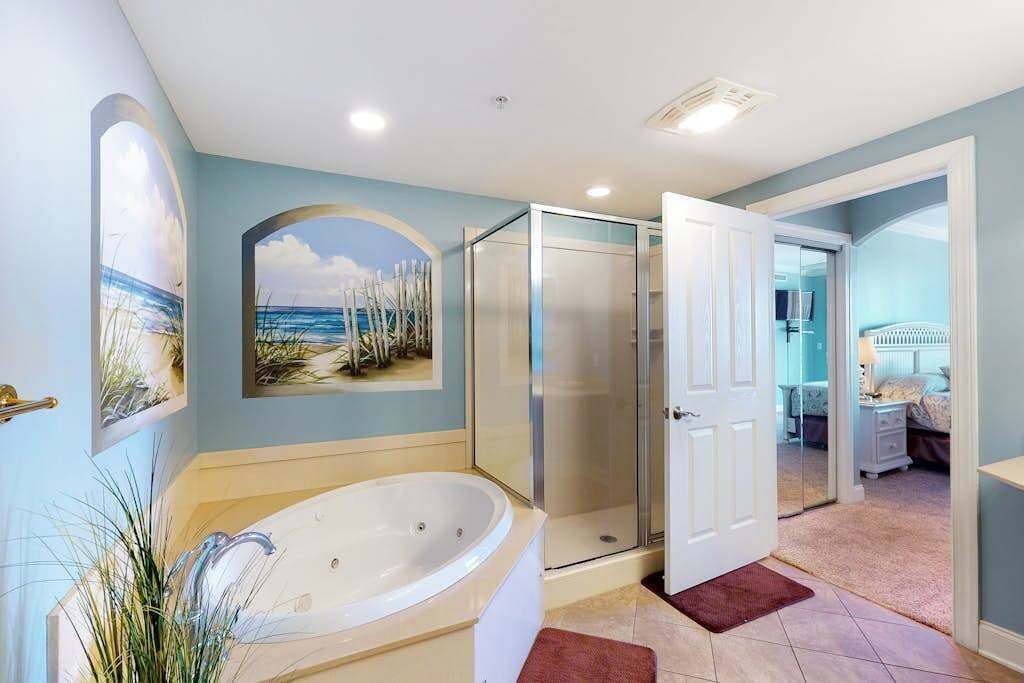 Une salle de bain avec une baignoire, une douche et une porte donnant sur une chambre.