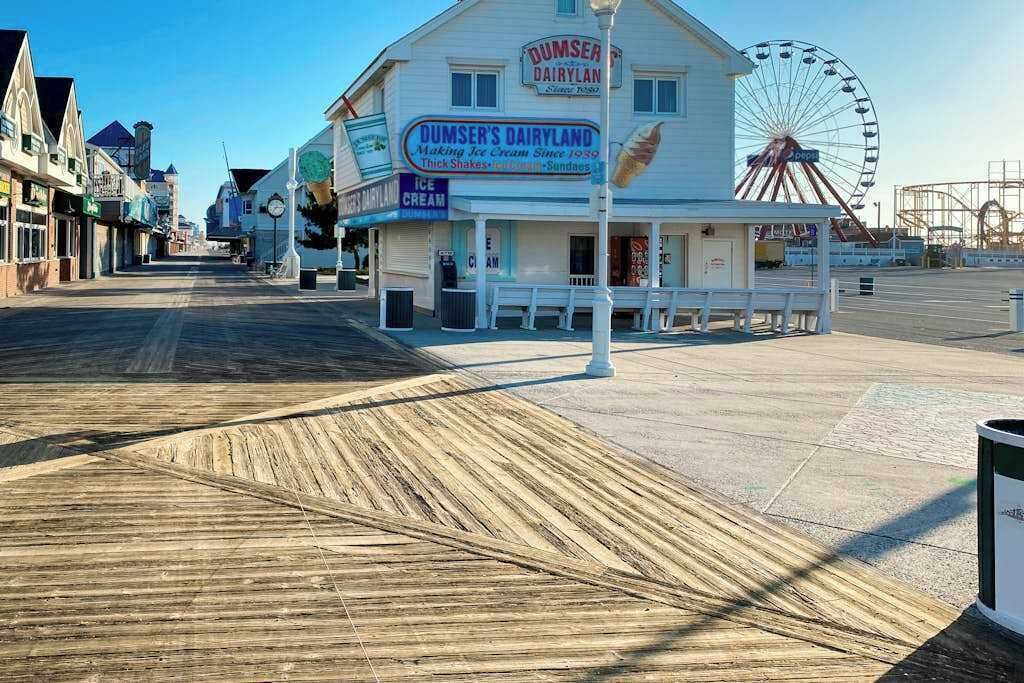 A boardwalk with Dumser's Dairyland ice cream shop, a Ferris wheel, and a vacant lot.