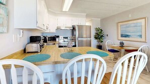 Eine moderne Küche mit weißen Schränken, Edelstahlgeräten und einem Holzespeisetisch mit weißen Stühlen.