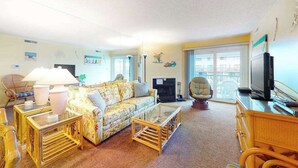 Ein Wohnzimmer mit Sofa, Couchtisch, Fernseher und Kamin.