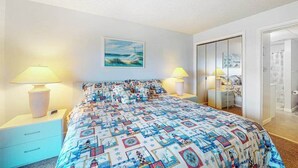 Ein Schlafzimmer mit einem Bett, zwei Nachttischen, einem Kleiderschrank und einer Tür zu einem Badezimmer.