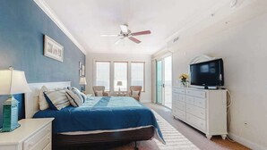 A bedroom with a bed, a TV, a dresser, and a ceiling fan. - Belmont Towers 505 (Ocean City)