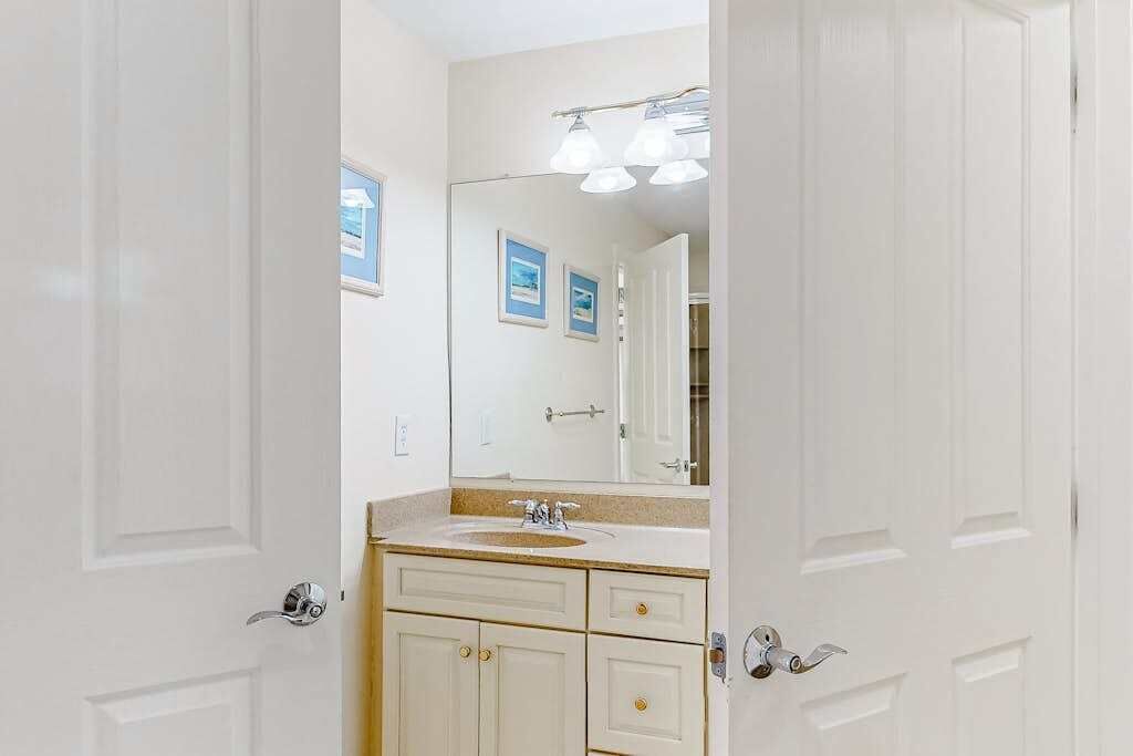 A bathroom with a white vanity, a sink, and a mirror.