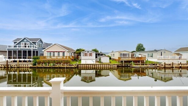 Une propriété située au bord de l’eau, comprenant plusieurs maisons, un quai et une rambarde blanche.