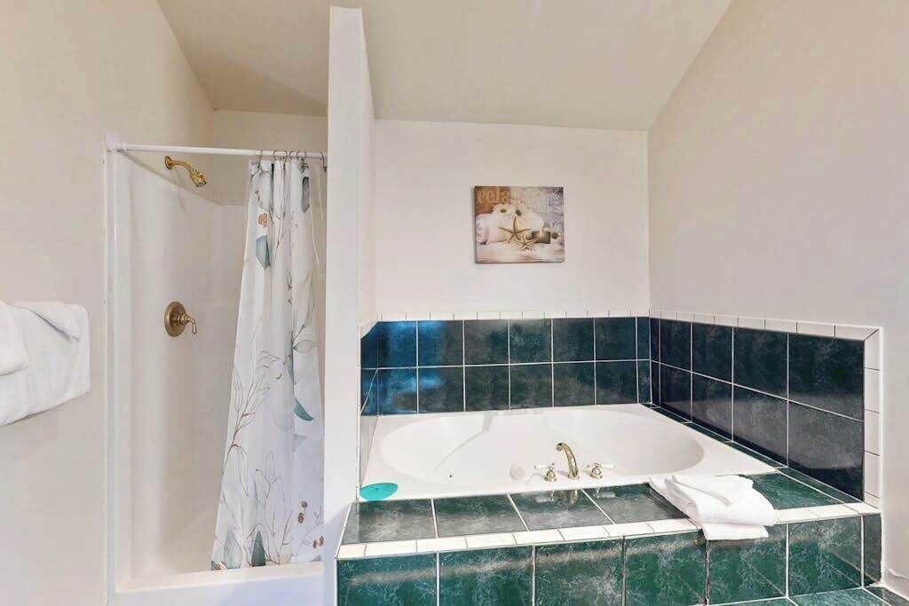 A bathroom with a bathtub, shower curtain, and a wall-mounted picture.
