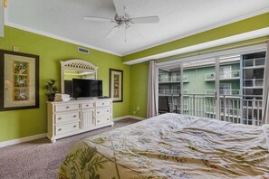 A bedroom with a bed, dresser, television, and a balcony with a railing. - Bay One 304 (Ocean City)